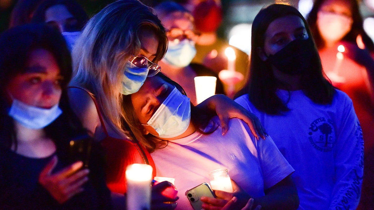 Mourners in face masks with candles lit.