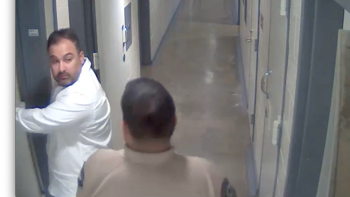 Joseph Iniguez looks over his shoulder at an officer as he enters a cell