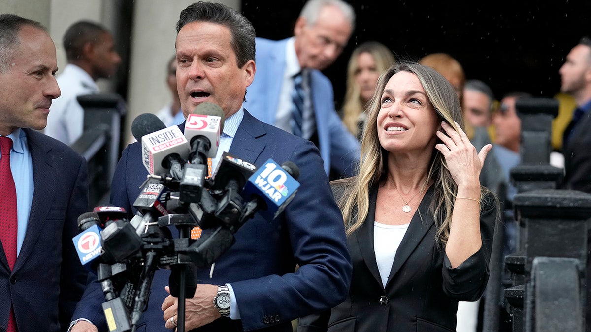 Karen Read, right, looks up as defense attorney Alan Jackson, center, speaks to reporters