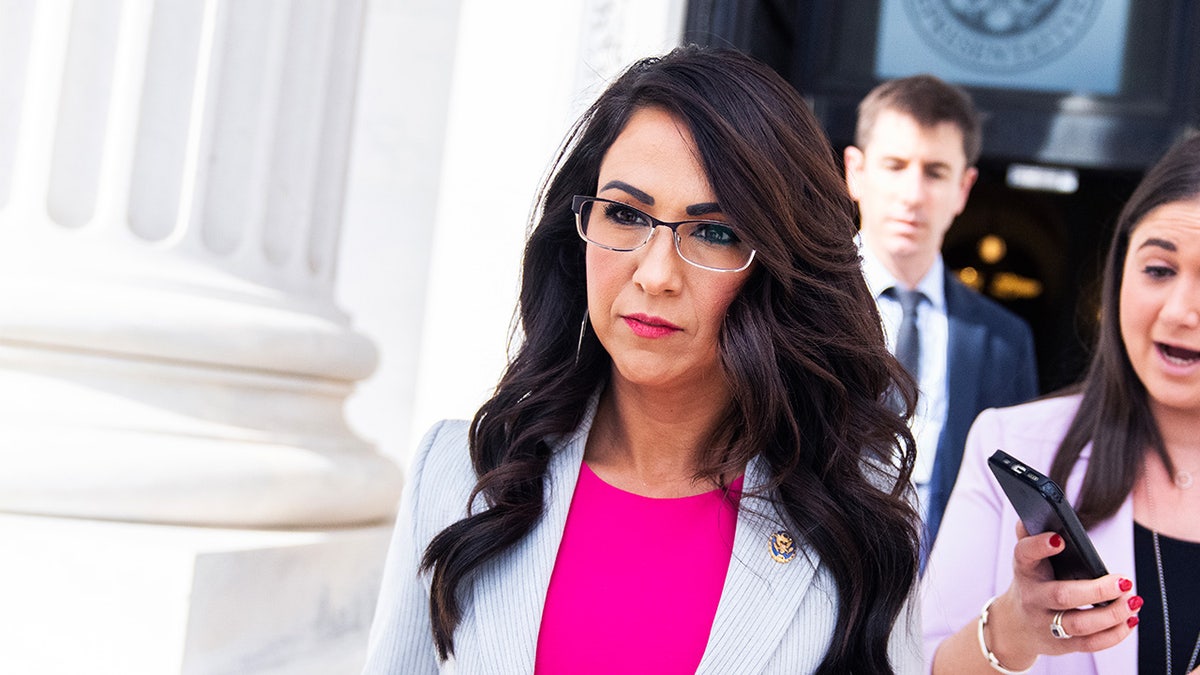 Rep. Lauren Boebert, a woman with glasses and long dark brown hair wearing a pink top, walks out of the U.S. Capitol