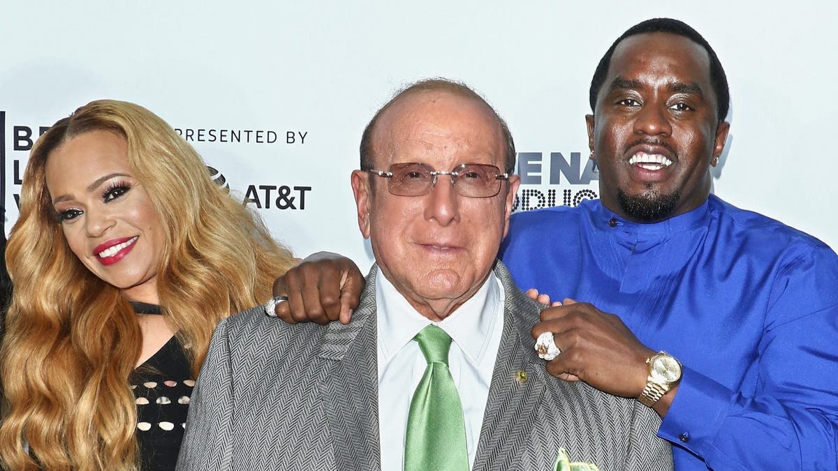 Singer Faith Evans, music producer Clive Davis and rapper/actor Sean Combs on a red carpet