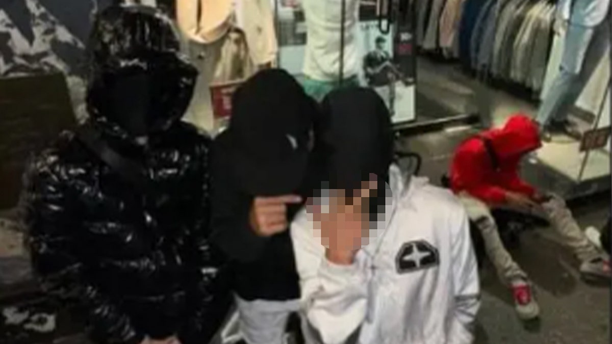 Suspected Tren de Aragua members with concealed faces make a rude gesture