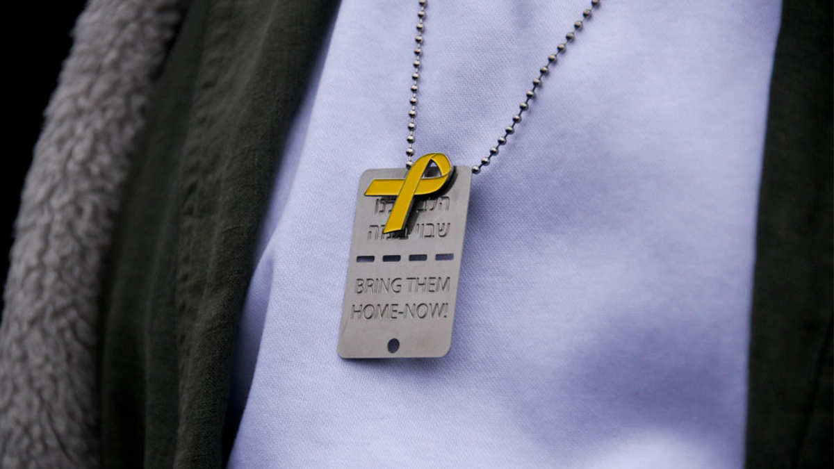 A bring them home necklace with a yellow ribbon pin