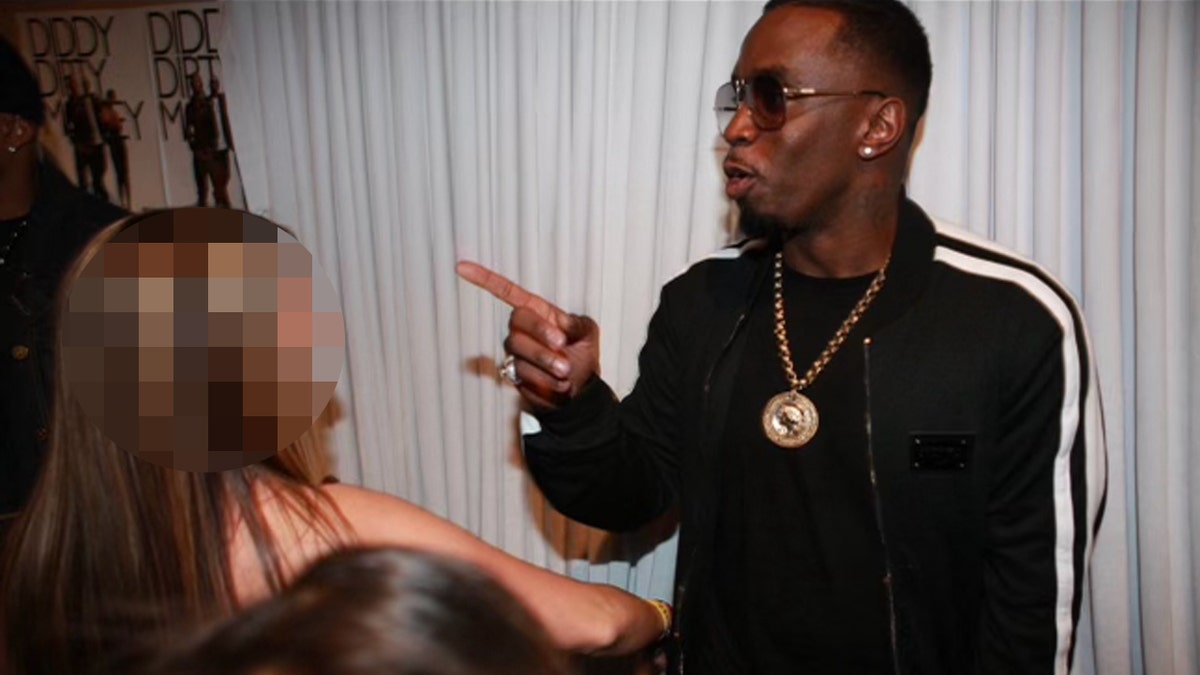 Sean 'Diddy' Combs gestures at a woman while wearing a black track suit