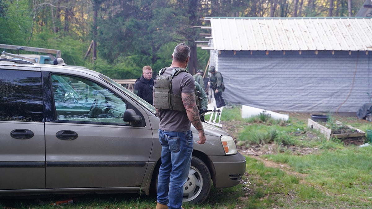 Lou Valoze turned away from the camera next to a car.