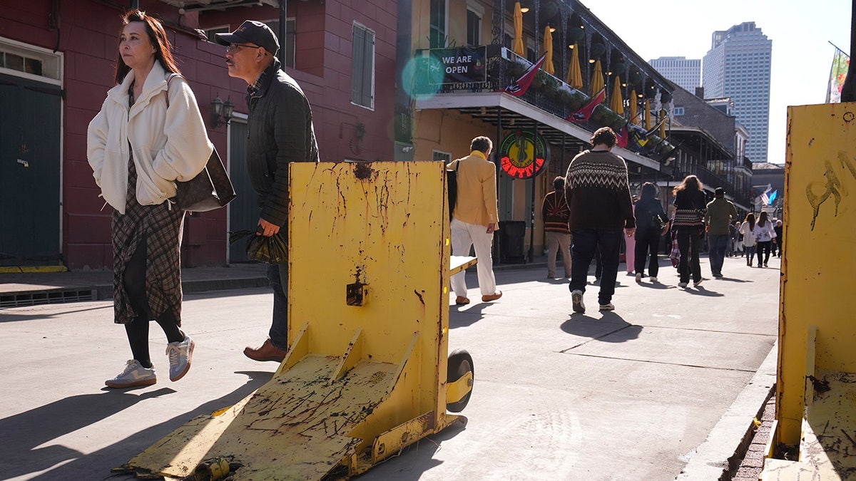 Tourist walk past temporary barriers on Orleans and Bourbon Street