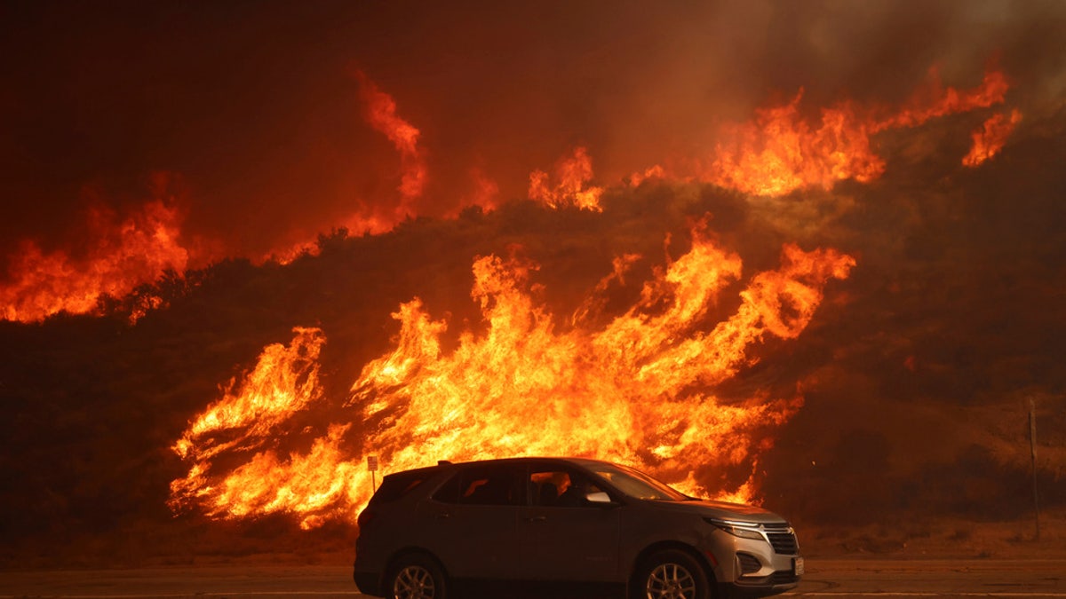 Car drives by raging wildfire in California