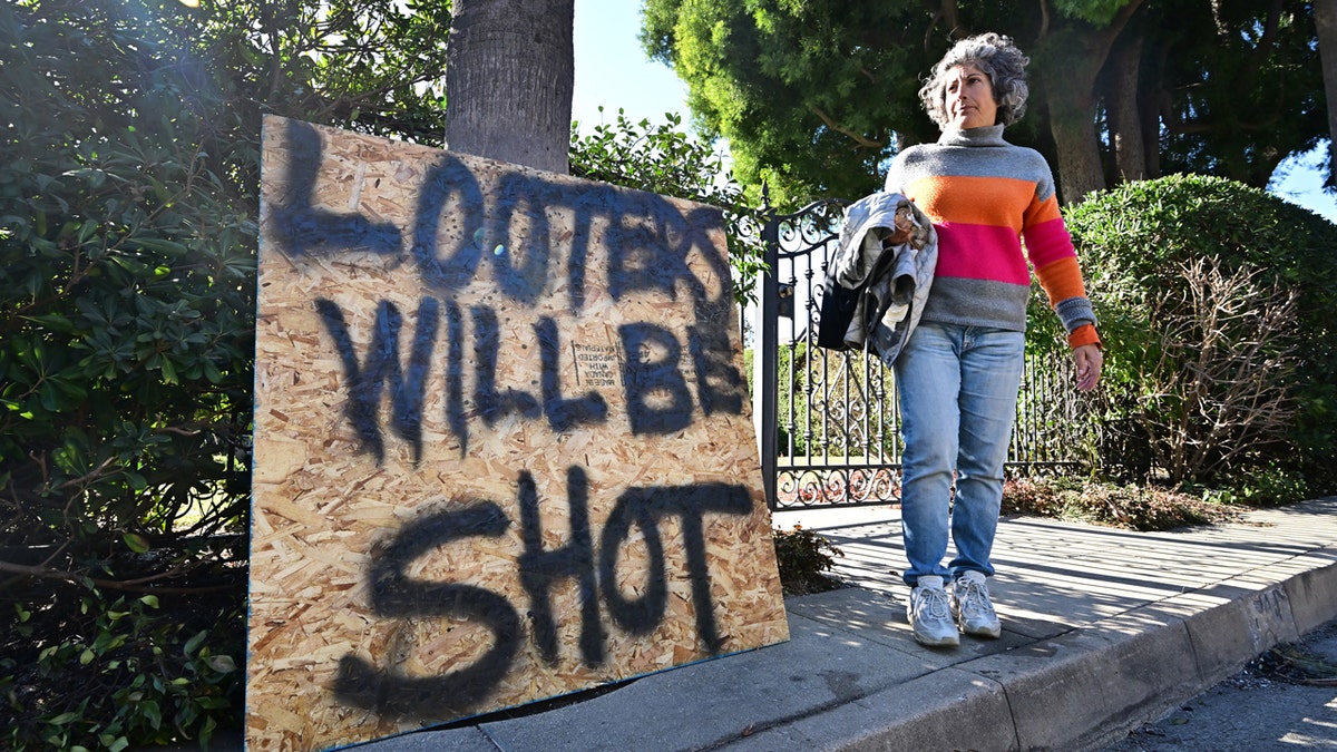 An Altadena resident walks past a sign 