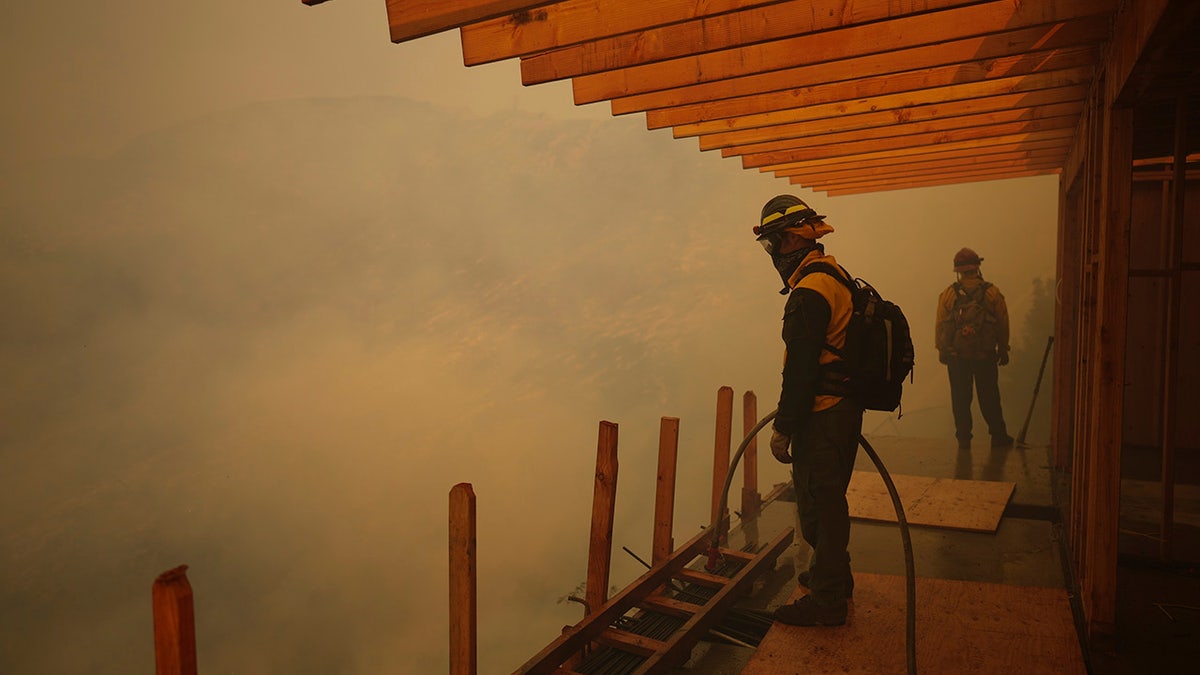 Firefighters monitor the advance of the Palisades Fire in Mandeville Canyon