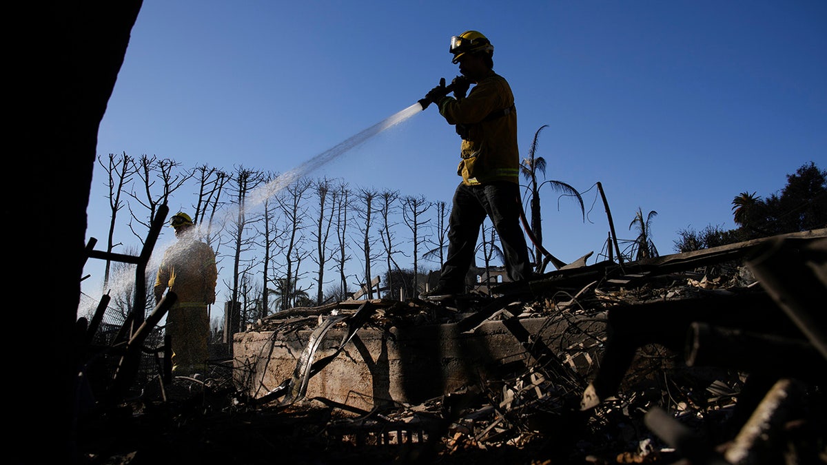 Tim Murphy, with the San Francisco Fire Dept., puts out hot spots in a burned property in the aftermath of the Palisades Fire