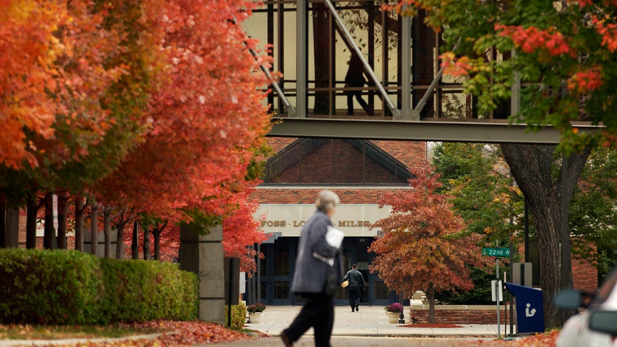 woman walks on augsburg university campus in fall with changing leaves