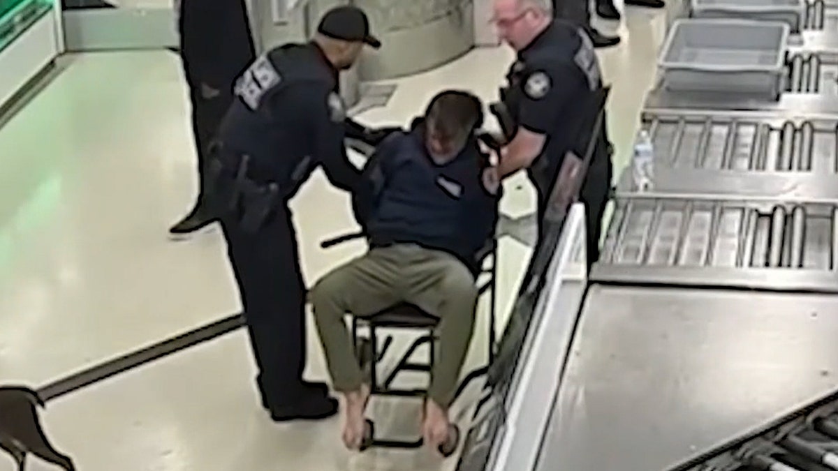 authorities detain man onto chair at airport