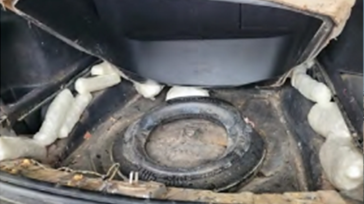 Bricks of wrapped drugs in the back of a filthy car trunk