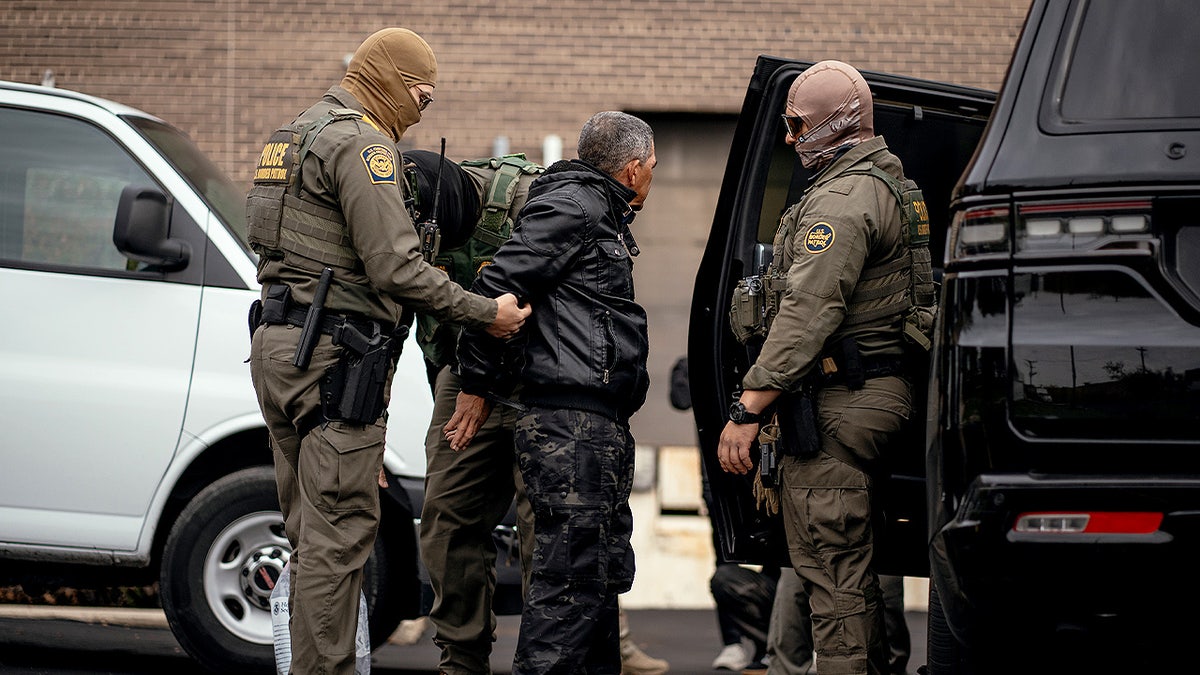 ICE agents detain a man in a parking lot