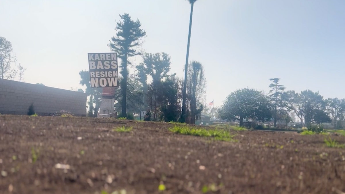 A sign calling for Los Angeles Mayor Karen Bass to resign is displayed on a vacant lot.