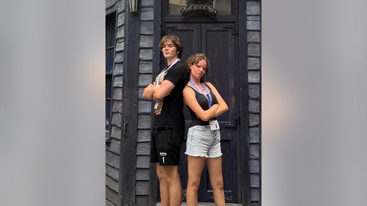 A boy and girl stand back-to-back with their arms crossed.