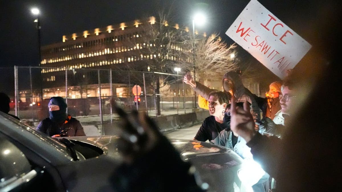 Fireworks explode above federal agents during a protest outside a Minneapolis federal building at night.