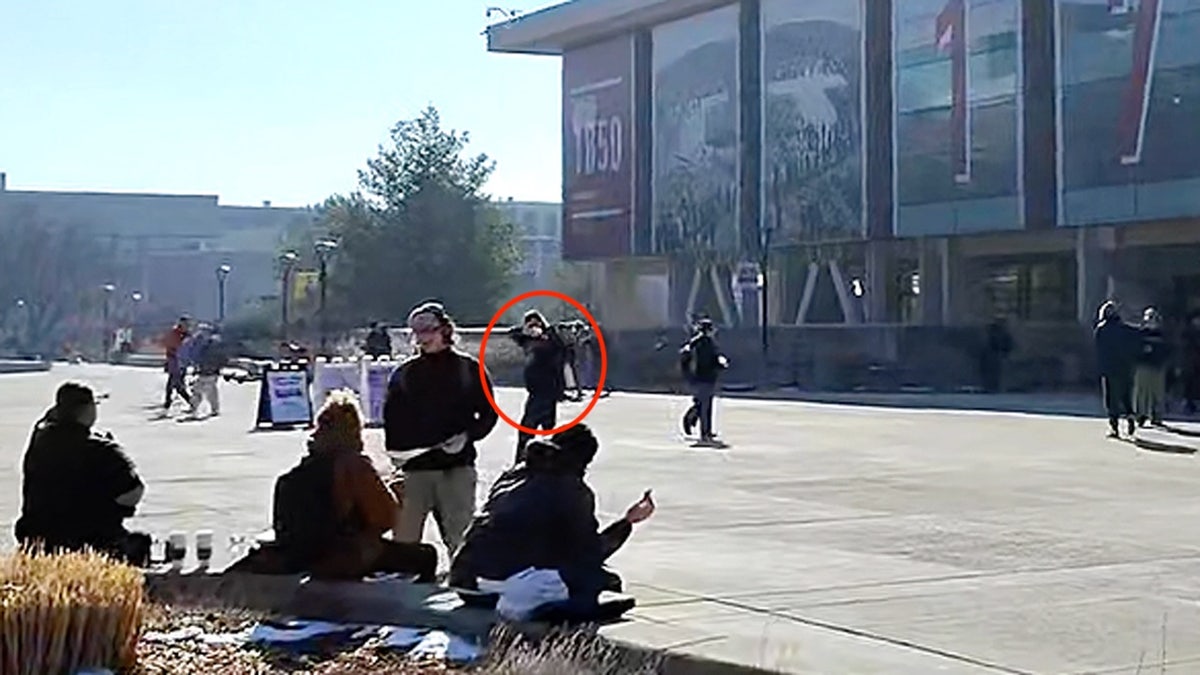 Student does a "shooting" motion at conservative debaters at the University of Utah circled in a red border