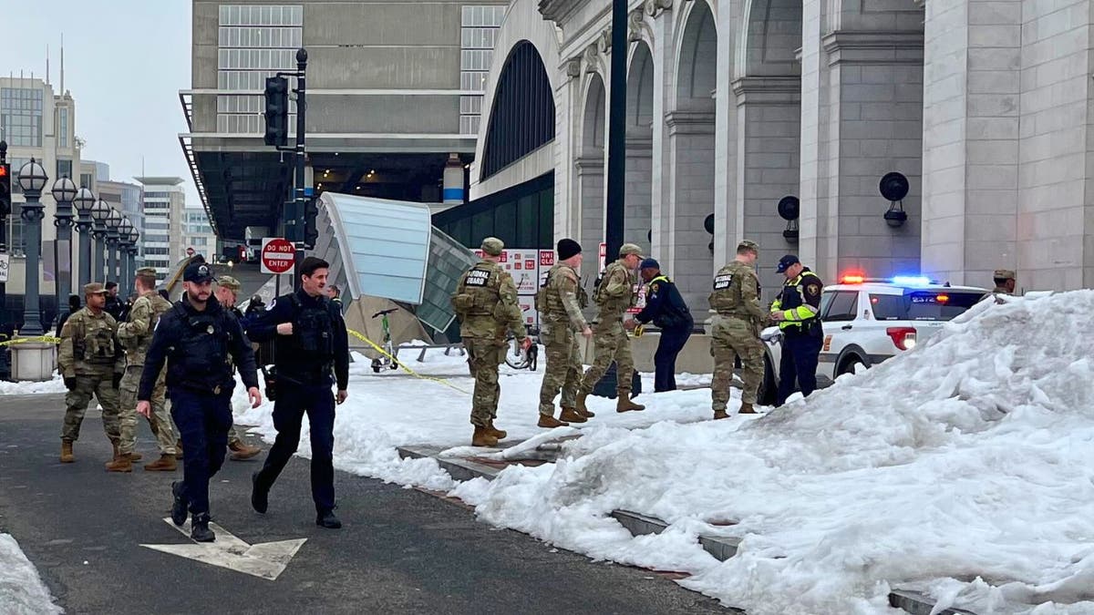 Police and security personnel stand near a taped-off street by the Capitol complex.