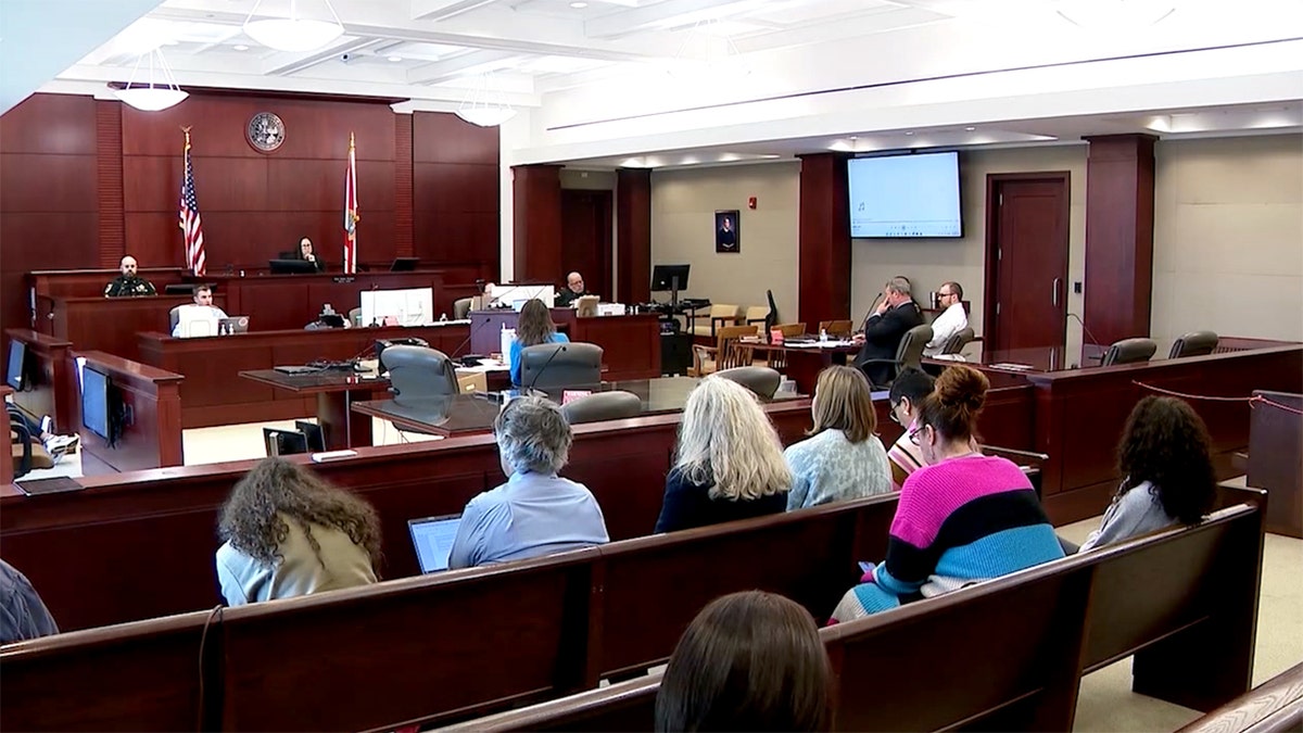 James Melady sits in courtroom as judge and others sit