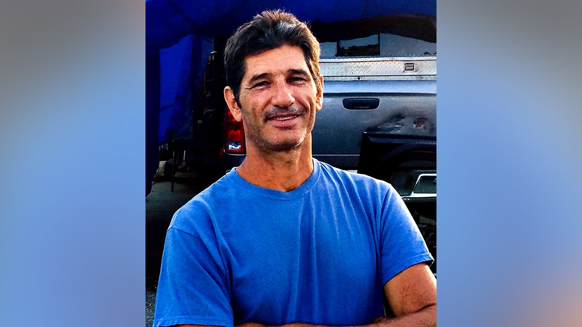 Kurt Van Dyke in blue shirt smiling with arms folded for a photo