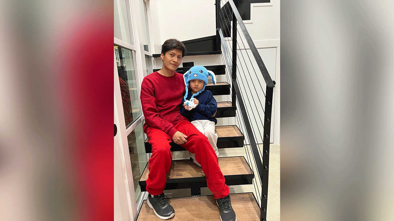 Adrian Alexander Conejo Arias and Liam Conejo Ramos sit together on indoor stairs.