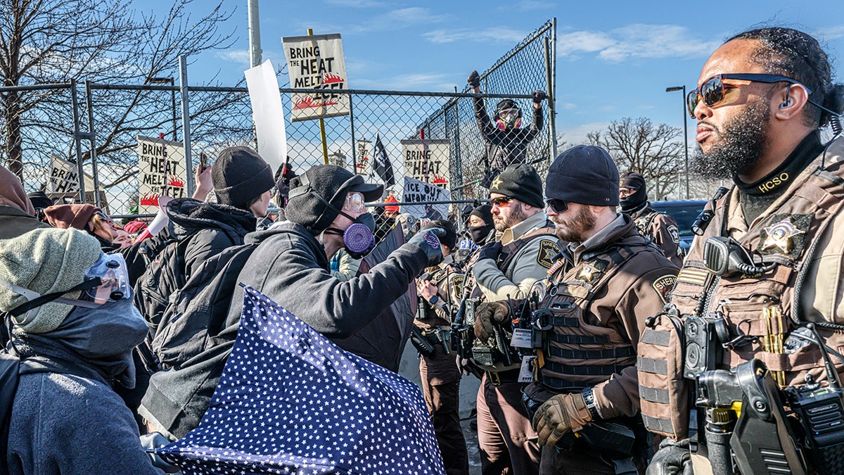Law enforcement stands guard as protestors demonstate outside the Bishop Henry Whipple Federal Building in Minneapolis