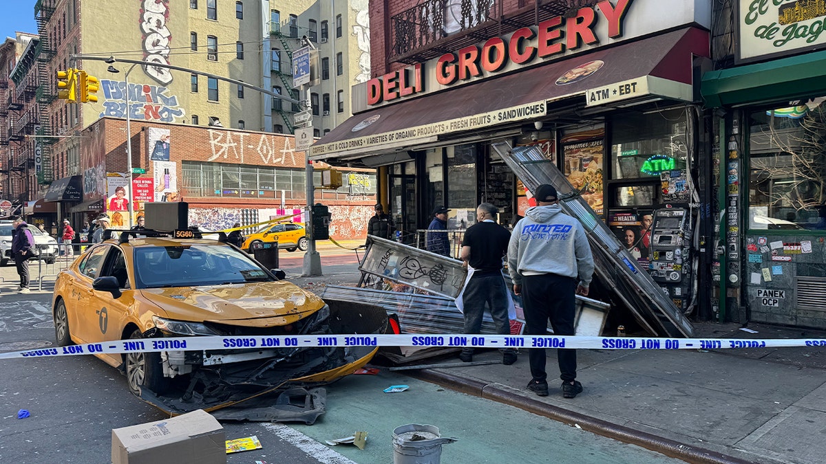 Police tape surrounds crashed NYC taxi outside deli grocery.