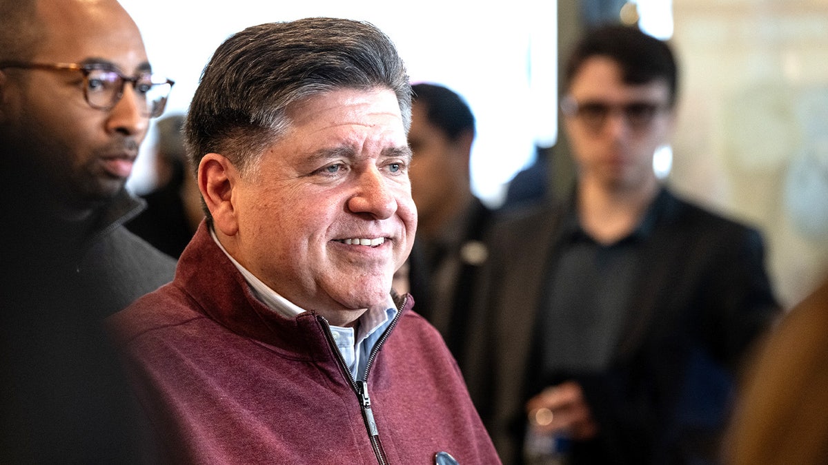 JB Pritzker speaking to members of the media while standing inside a cafeteria.