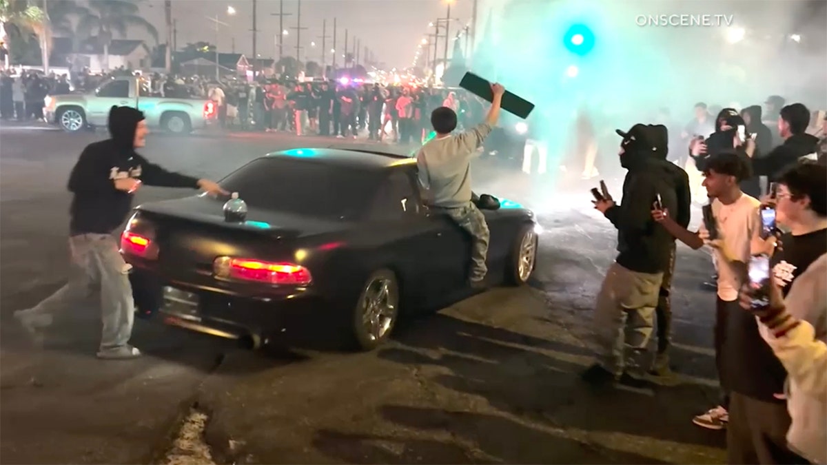 black sedan doing donuts street takeover