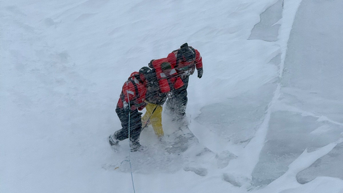 U.S. Coast Guard ice rescue team members help an individual onto a cutter after reaching them on frozen Lake Huron.
