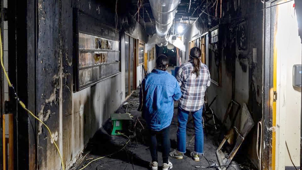 People in a hallway that appears to be partially destroyed.