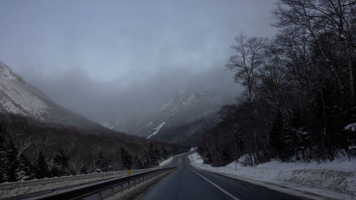 Fog hovering over a narrow road in Franconia Notch in White Mountain National Forest