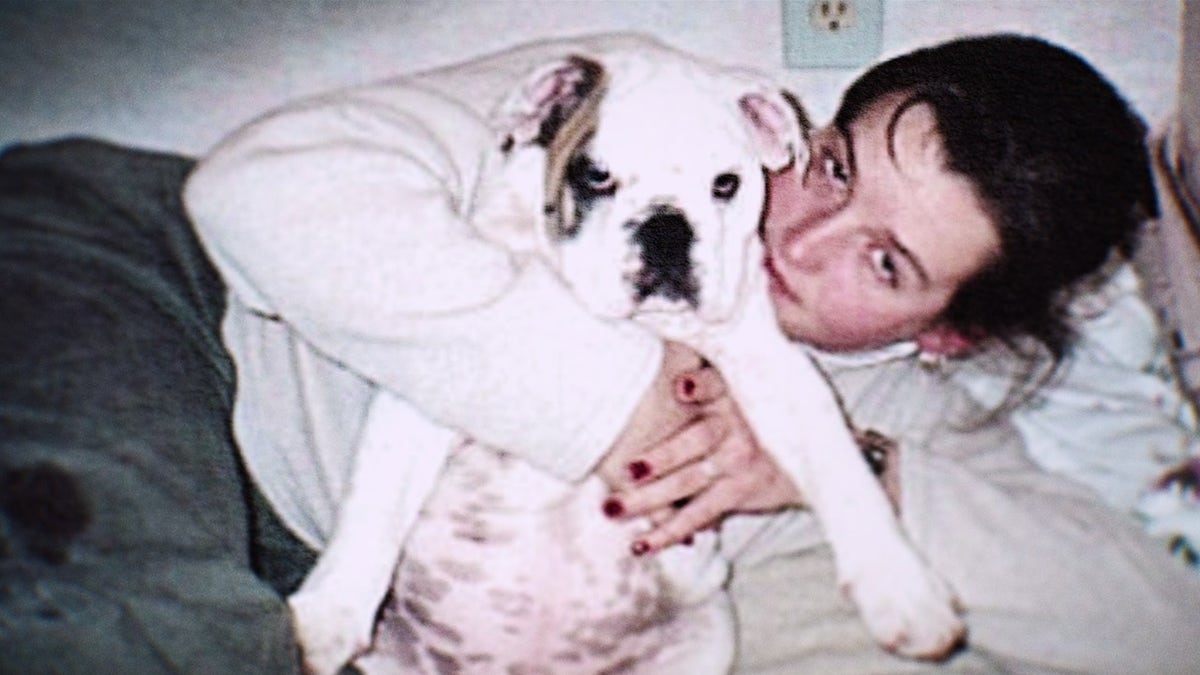 Amy Bradley wearing a white sweater holding her bulldog.