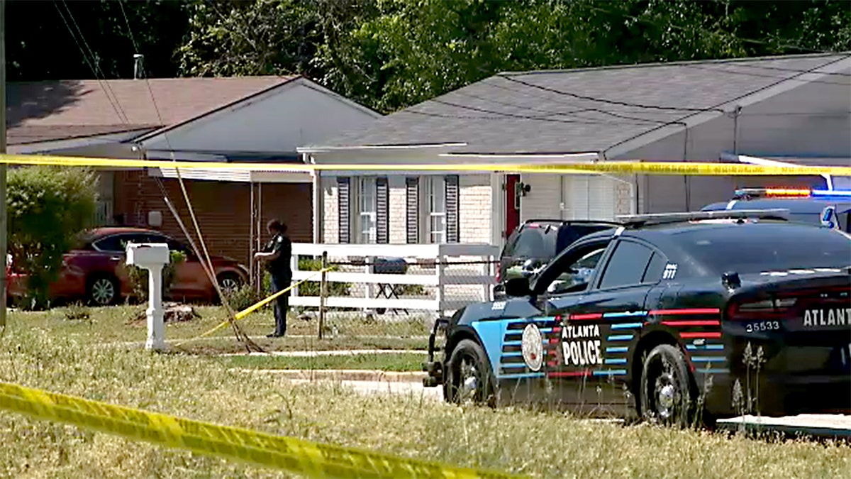 An Atlanta Police car sits in front of a house with police tape.