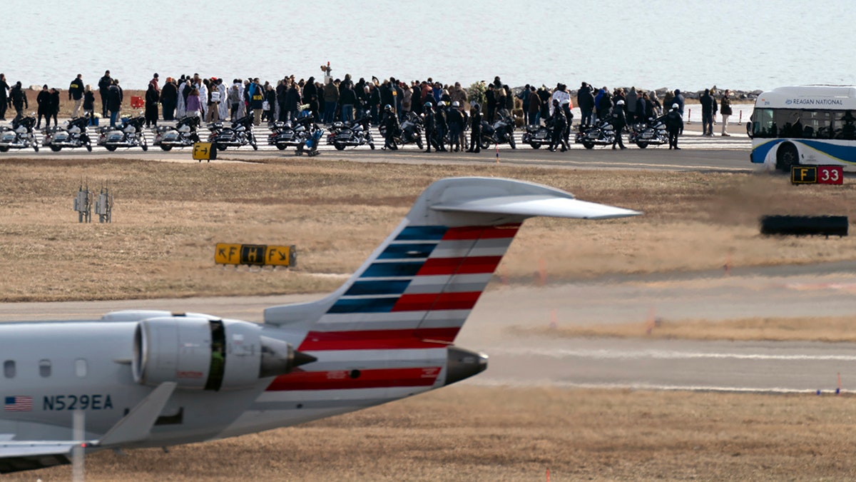 Family members standing near wreckage site of American Airlines jet and Army helicopter collision