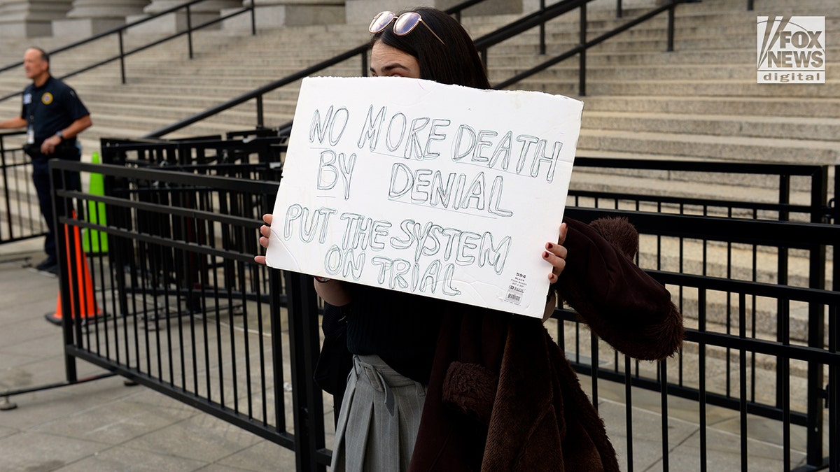 A Luigi Mangione supporter standing with a sign outside a Manhattan court.