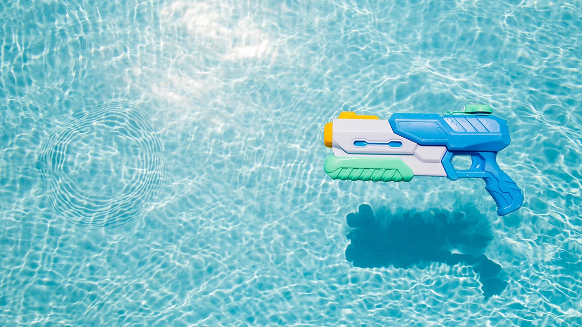 A child's blue water gun floating in a pool.