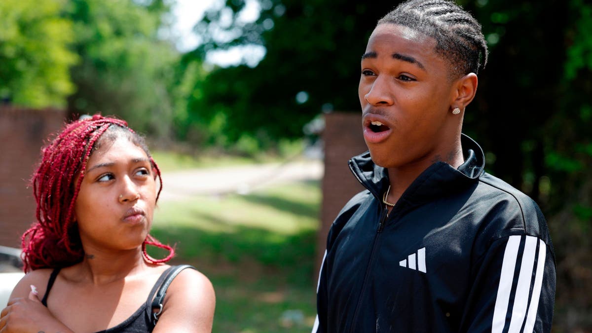 A redheaded woman stares up at a young man with tight braids