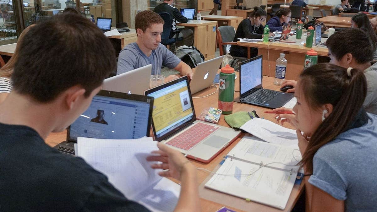 College students on laptops and studying in library