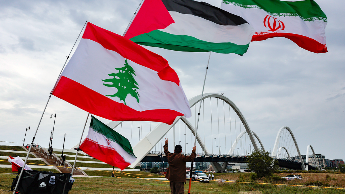 A protester against the U.S. war in Iran standing at the base of the Frederick Douglass Memorial Bridge