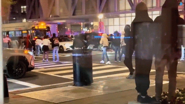 Teens run through a busy intersection.