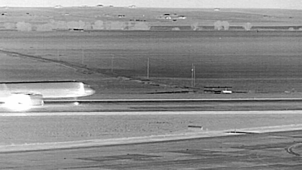 Unidentified person climbing perimeter fence at Denver International Airport in thermal imaging