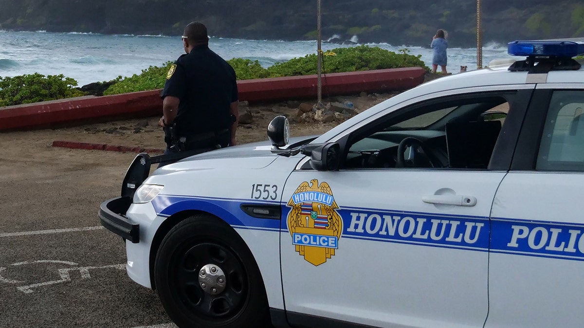 Honolulu police officers standing on a street in Chinatown at night