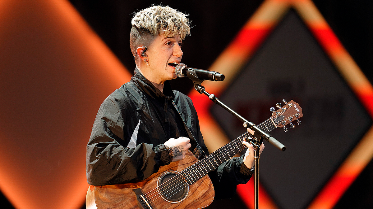 Singer Jack Avery performs onstage with a guitar during a live performance