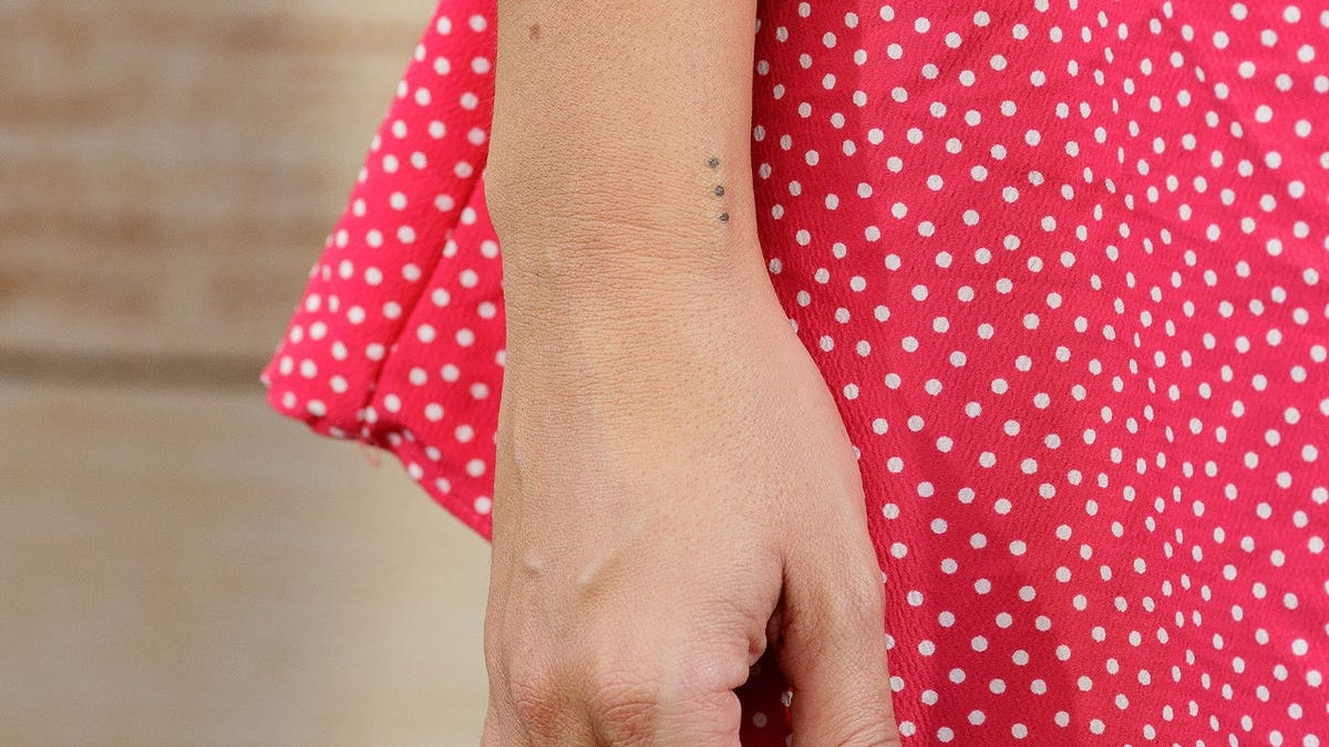 Three "party dot" tattoos are seen on a wrist