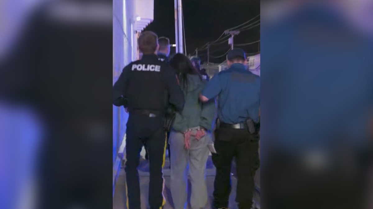 Assemblyman Paul Kanitra escorting a cuffed man on a Jersey Shore boardwalk at night