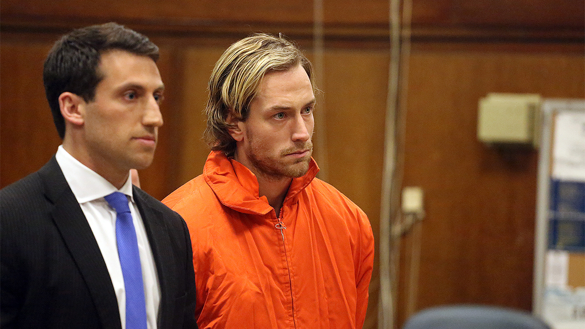 Thomas Gilbert Jr. stands in court wearing an orange jail uniform during his Manhattan murder case