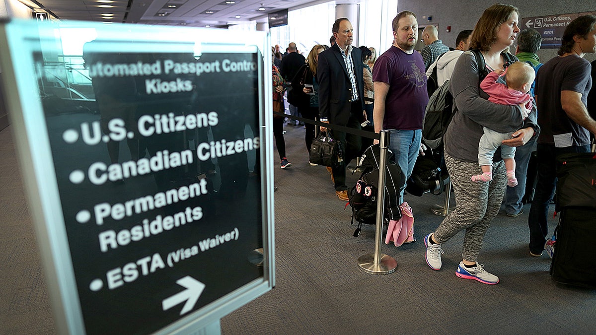 Passengers waiting in line to use Automated Passport Control Kiosks at Miami International Airport