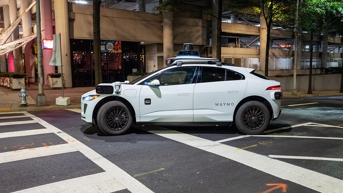 Waymo self-driving car navigating a street at night in downtown Atlanta